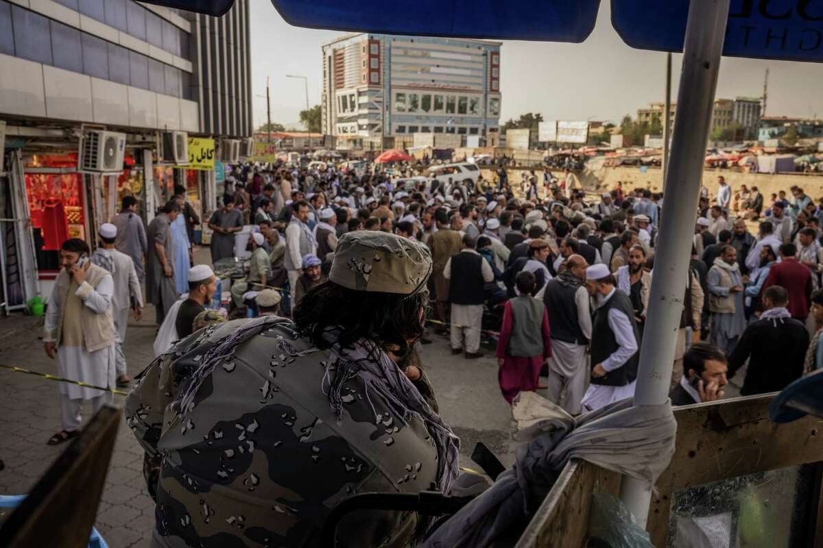 A member of the Taliban watches over a crowd gathering outside the main currency exchange in Kabul, Afghanistan, on Sunday, Aug. 29, 2021. A U.S. drone strike on Sunday destroyed an explosives-laden vehicle that the Pentagon said posed an imminent threat to Afghanistan's main airport, as the massive airlift of Afghans fleeing Taliban rule shut down just two days before the scheduled final withdrawal of American forces. (Jim Huylebroek/The New York Times)