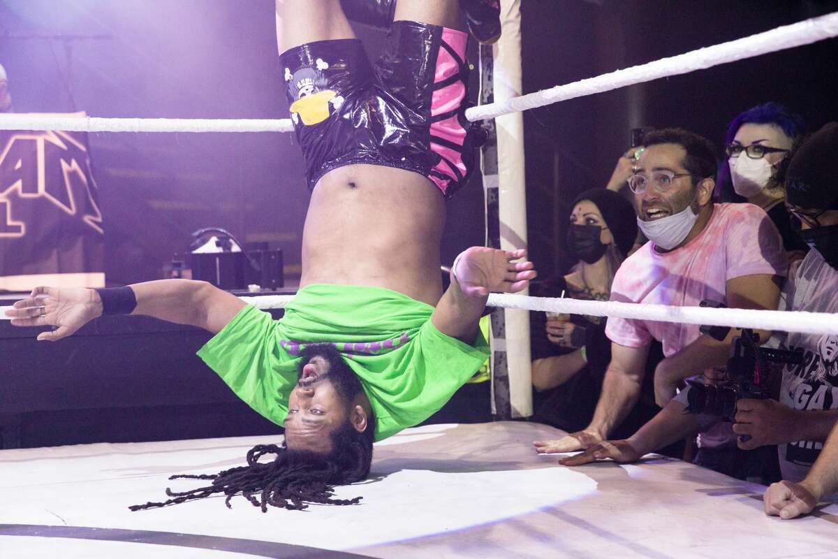 Wrestler D-Rogue hangs on the ropes upside-down as the crowd cheers him on during Hoodslam at DNA Lounge in San Francisco on Aug. 22, 2021.