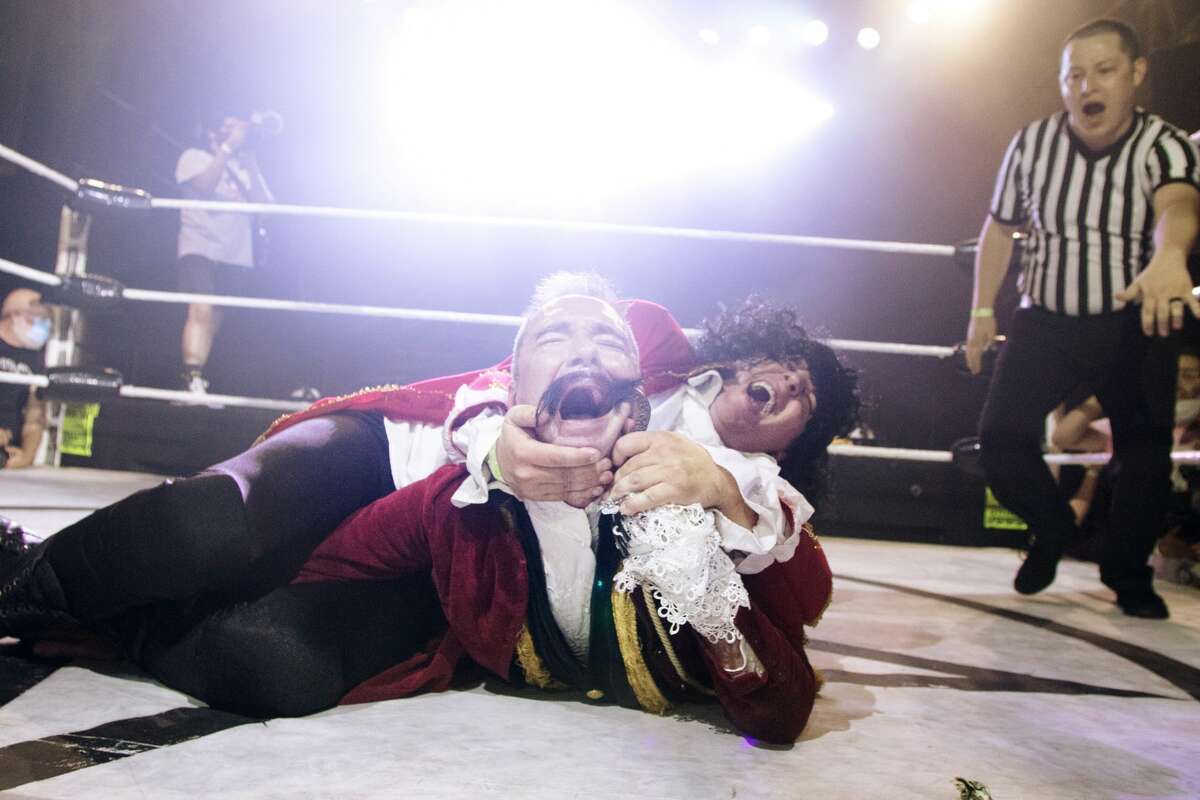 Wrestler Captain Hook, center, is held down by Cap'n Morgan while Referee Wiggles looks on during Hoodslam's return at DNA Lounge in San Francisco on Aug. 22, 2021.