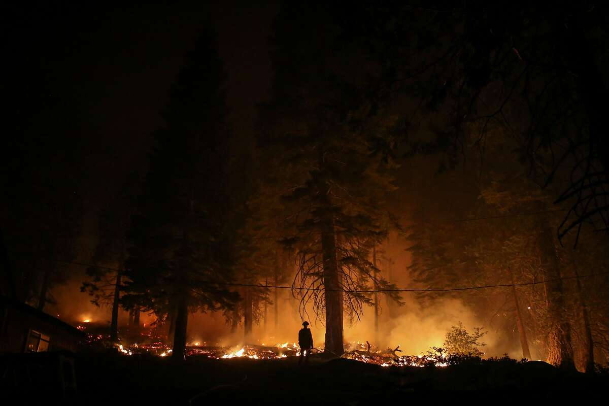 A firefighter monitors a large blaze a part of the Caldor Fire near a home near Strawberry, Calif. on Sunday, Aug. 29, 2021.