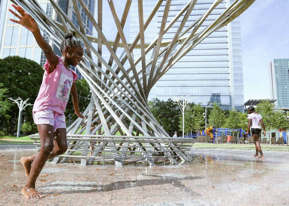 Makiya Dowdell, 8, left, cools off with her cousin, Jazzy Knowles, 10, at Houston's Discovery Green Park on Monday, Aug. 2, 2021.