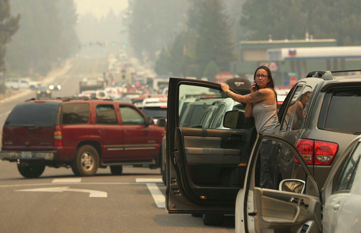 A woman talks on her phone while stopped in heavy traffic on Hwy 50 as people evacuate ahead of the Caldor Fire on August 30, 2021 in South Lake Tahoe.