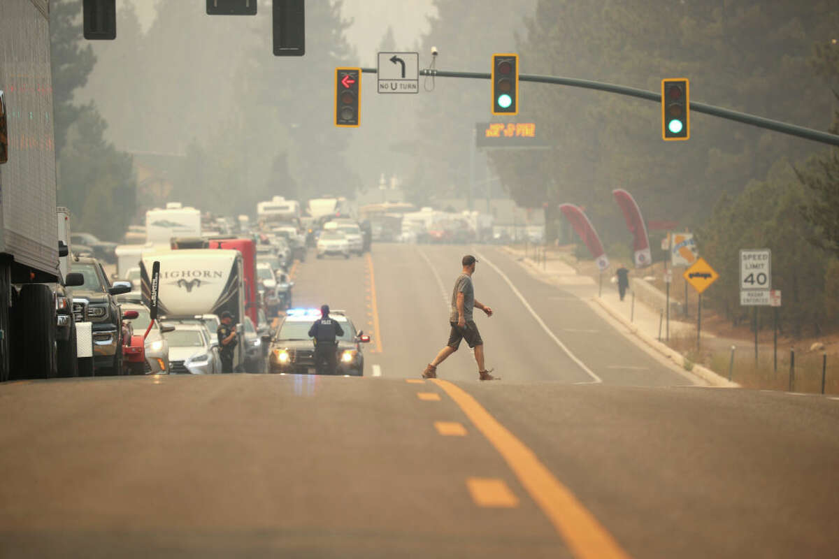 Un piéton traverse la rue alors que la circulation ralentit sur l'autoroute 50 alors que les gens évacuent avant l'incendie de Caldor le 30 août 2021 à South Lake Tahoe.