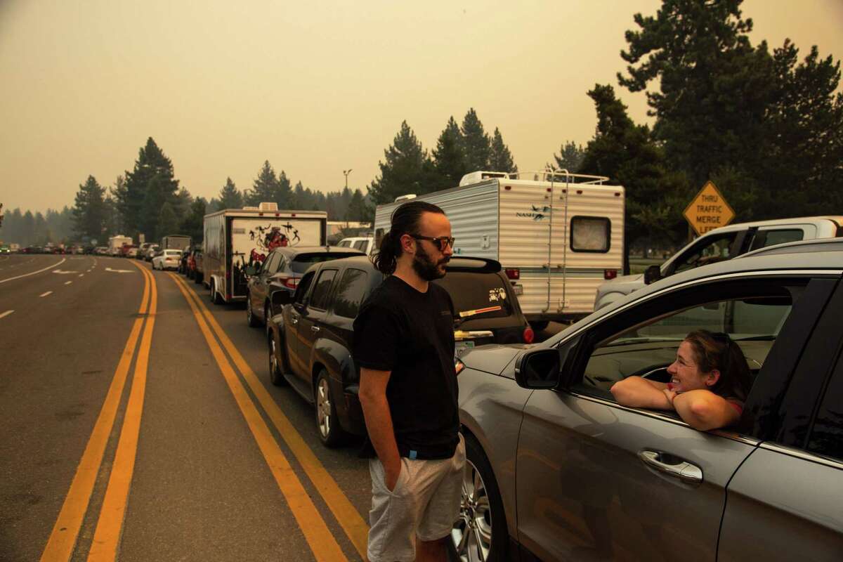 Shawn Hoffman, left, talks with his partner Madison Sites while they wait in eastbound evacuation traffic on Highway 50 after mandatory evacuation orders were issued to all of South Lake Tahoe, Calif. due to the approaching Caldor Fire.