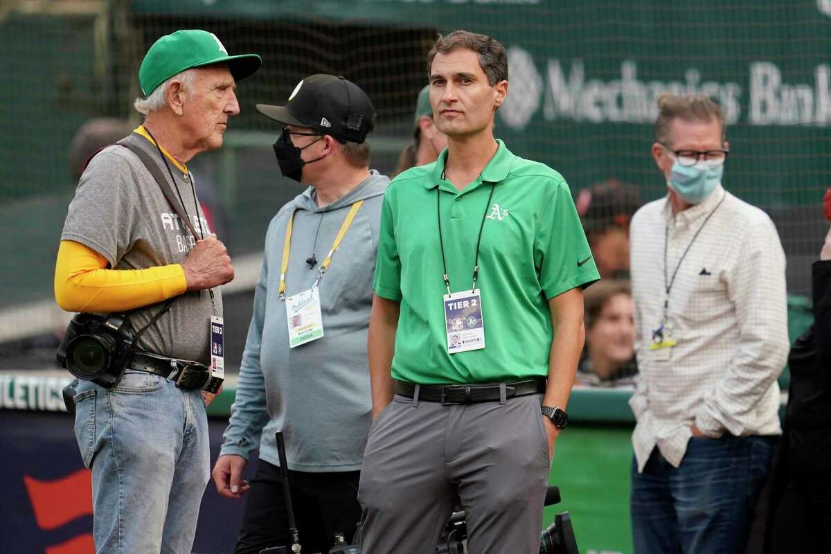 Oakland Athletics President Dave Kaval, center, talks with photographer Michael Zagaris, left, before a baseball game between the Athletics and the San Francisco Giants in Oakland, Calif., Friday, Aug. 20, 2021. (AP Photo/Jeff Chiu)
