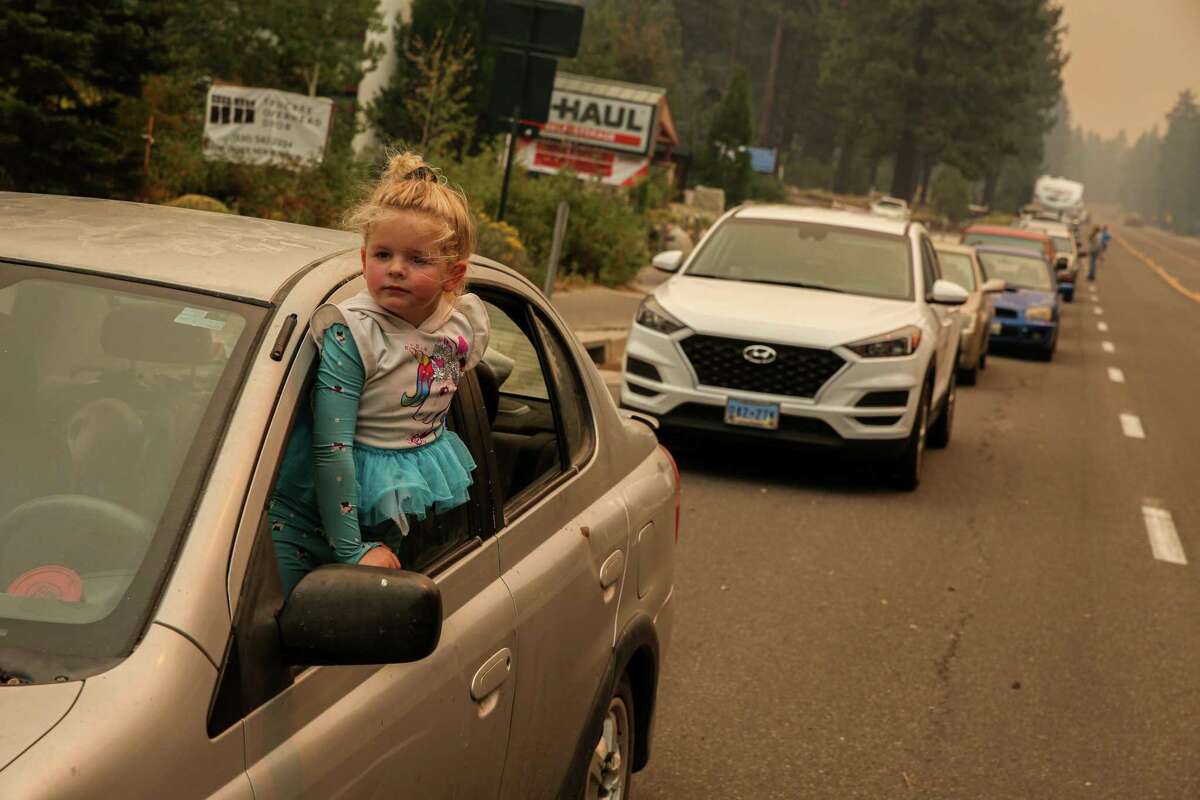 Three-year-old Madeleine Castellanos and her mother wait in an evacuation line on Highway 50 in South Lake Tahoe on Monday due to the threat of encroaching wildfire flames from the Caldor Fire.