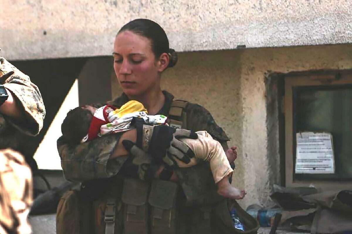 Sgt. Nicole Gee of Sacramento, shown holding a baby at Hamid Karzai International Airport in Kabul in a photo posted Aug. 20 on Twitter, was killed in Thursday’s bombing in Kabul.
