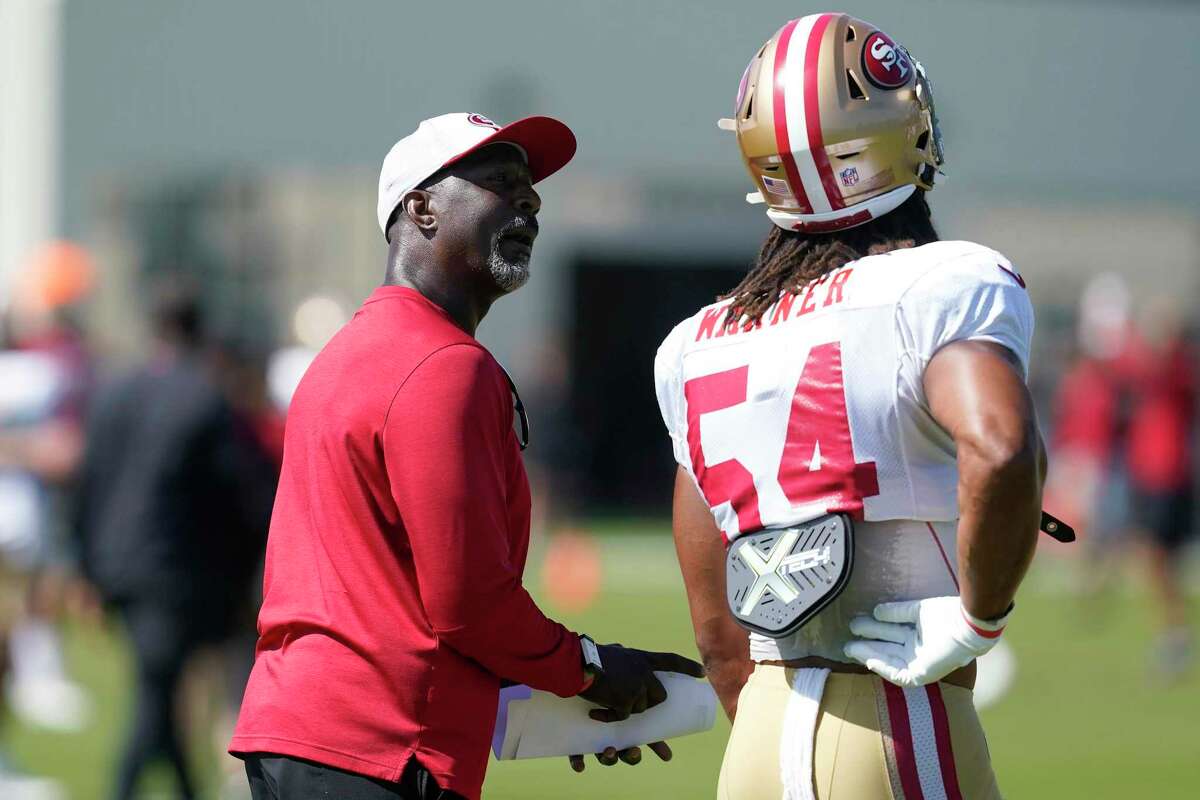 San Francisco 49ers linebackers coach Johnny Holland, left, talks with middle linebacker Fred Warner (54) at NFL football training camp in Santa Clara, Calif., Tuesday, Aug. 10, 2021. (AP Photo/Jeff Chiu)
