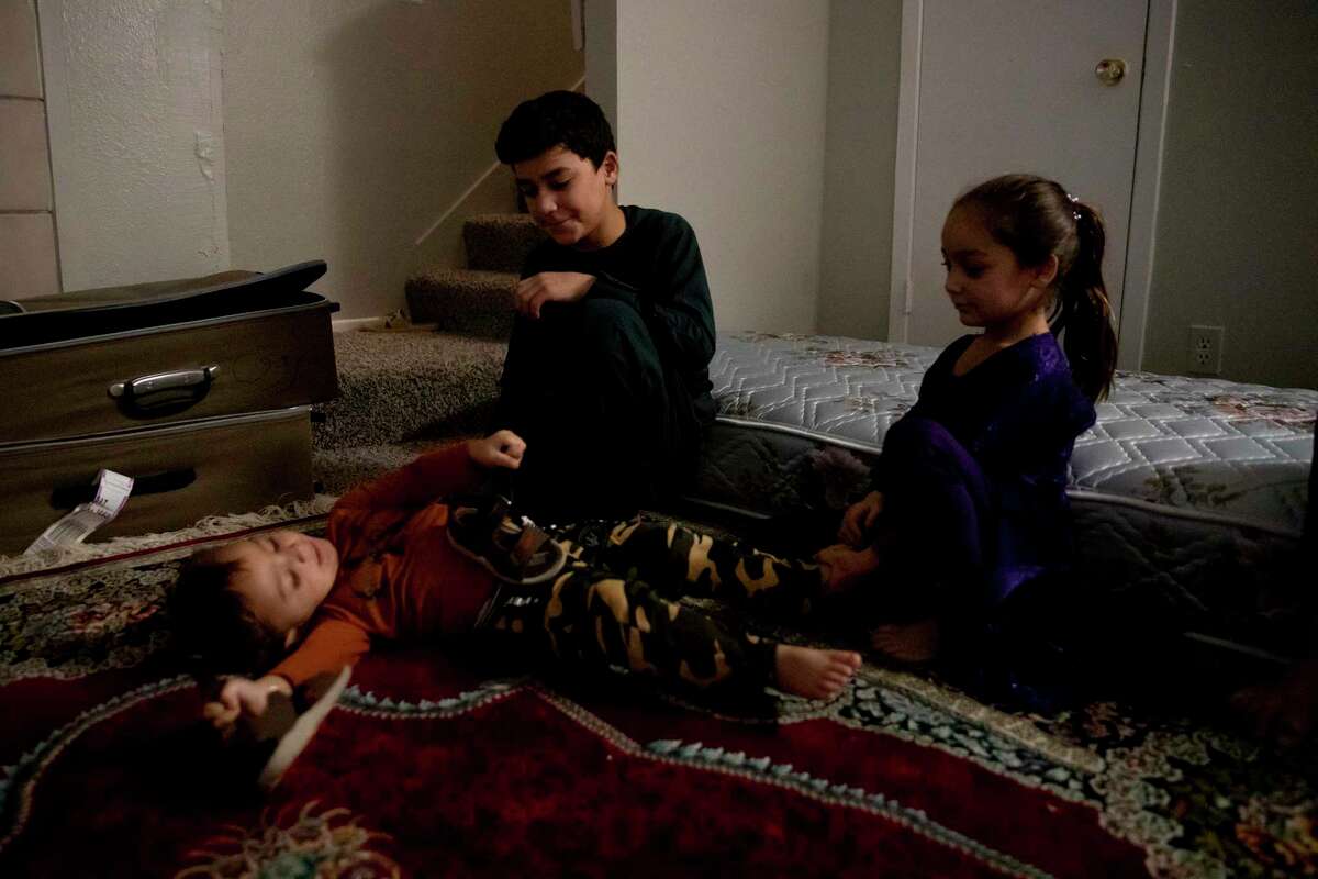Imal Moeen Shah and his siblings, Sayeera and Tasal, sit with each other while their father, Farooq Moeen Shah, talks with friends. The siblings and their mom have joined their father in San Antonio from Afghanistan after fleeing the Taliban.