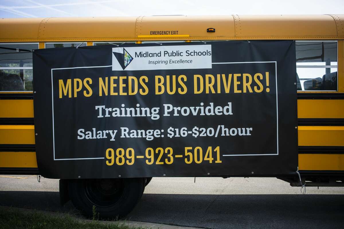 A bus is parked outside of Midland High School with a sign advertising that Midland Public Schools is looking to hire bus drivers Tuesday, Aug. 31, 2021. (Katy Kildee/kkildee@mdn.net)
