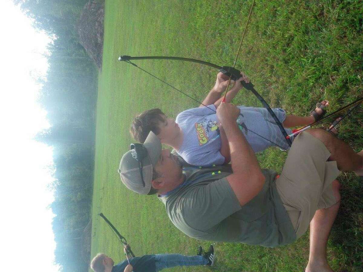 Experienced bowhunter Nick Chippi of Cass City tutors his 8-year-old son, Wyatt, on the archery range during the recent Free Youth Day at the Cass City Gun Club. (Tom Lounsbury/Hearst Michigan)