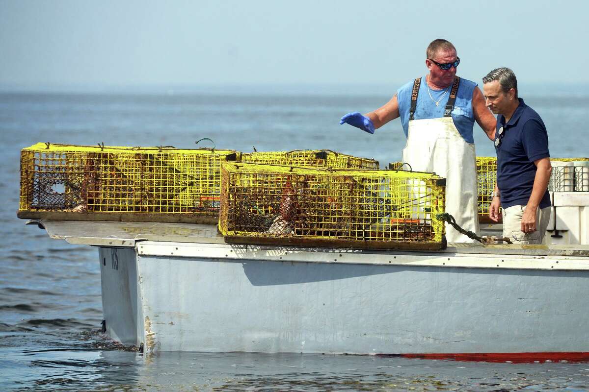 Lobsterman Mike Kalaman speaks with State Sen. Bob Duff onboard the Dark Horse while he pulls up his lobster traps on Long Island Sound, off the coast of Norwalk, Conn. Aug. 31, 2021.