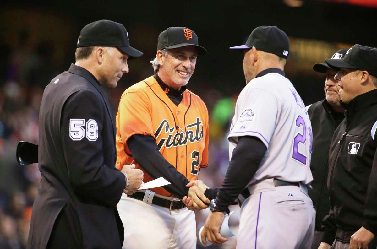 San Francisco Giants bench coach Ron Wotus, center, shakes hands with Colorado Rockies manager Walt Weiss before the start of a baseball game Friday, April 11, 2014, in San Francisco. At left is home plate umpire Dan Iassogna. (AP Photo/Eric Risberg)