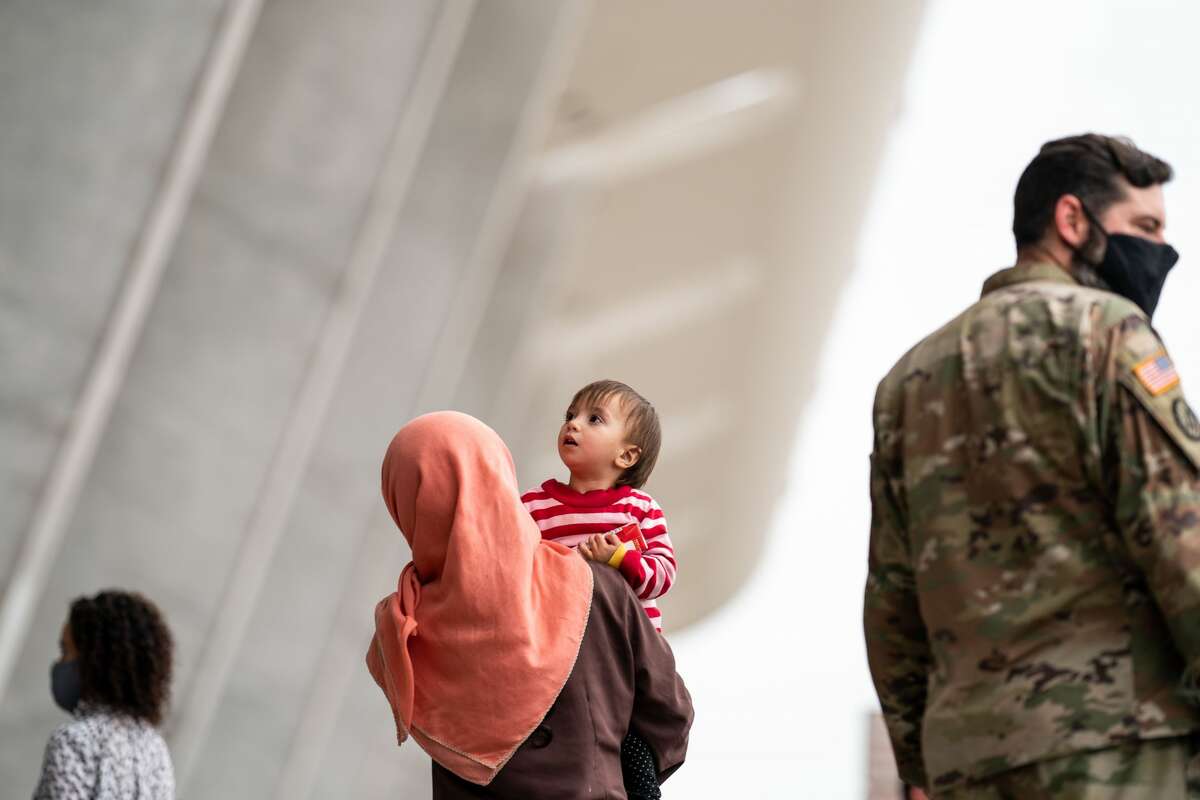 Evacuees who fled Afghanistan walk through the terminal to board buses that will take them to a processing center, at Dulles International Airport on Tuesday, Aug. 31, 2021. (Kent Nishimura/Los Angeles Times via Getty Images)