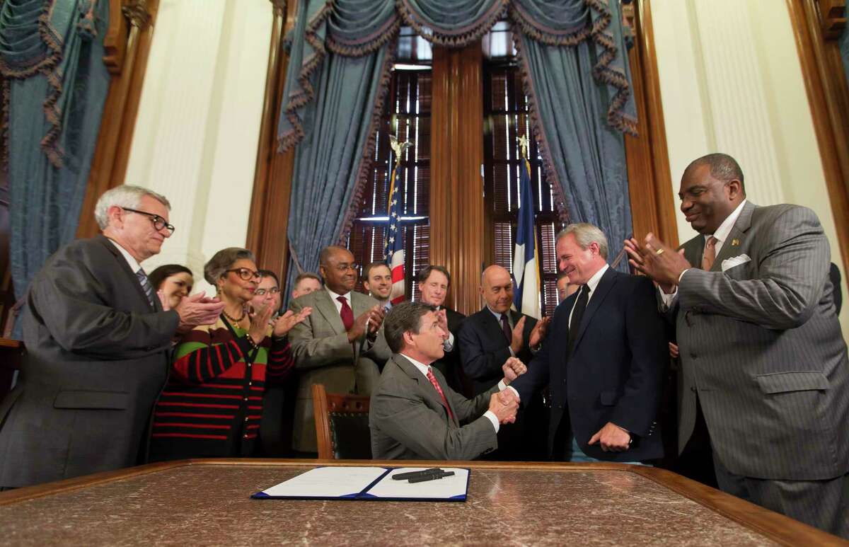 Gov. Rick Perry presents Michael Morton with a pen after signing the Michael Morton Act into law in 2013. A new state law builds on requirements for disclosing evidence.