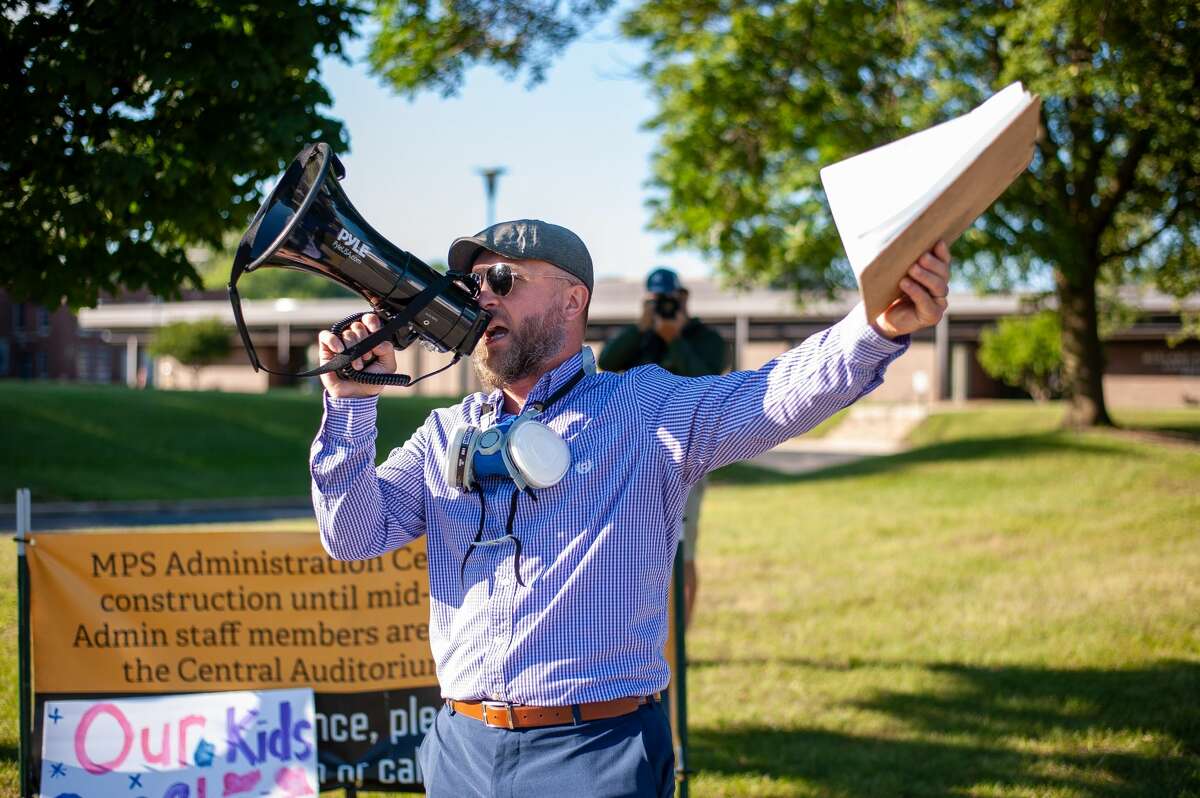 Jacob Lewis shouts into a megaphone on Sept. 1, 2021 by the Midland Public Schools Administration Building. He is protesting against the recent mask mandate made by the school.