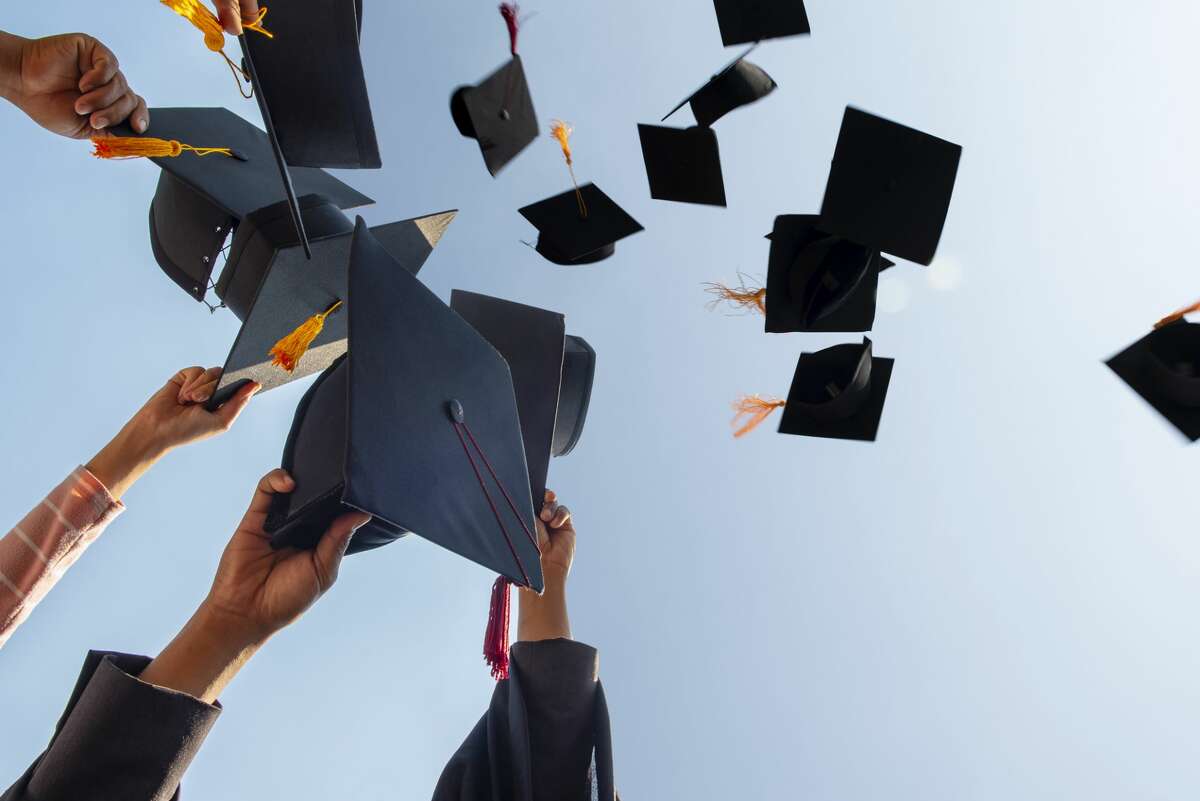 FILE: A group of graduates toss their caps in the air. 
