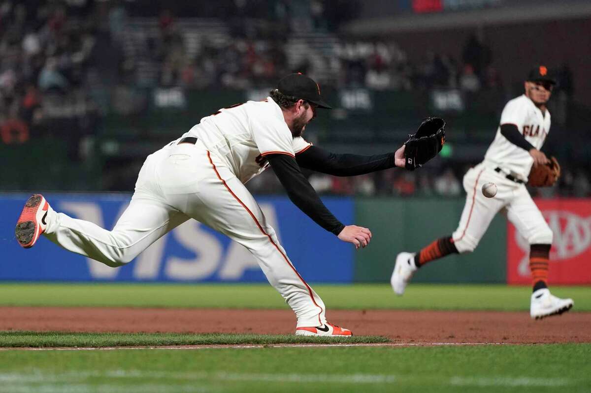San Francisco Giants pitcher Dominic Leone, left, cannot catch the throw from first baseman Brandon Belt, who was charged with an error, on an infield single by Milwaukee Brewers' Jackie Bradley Jr. during the seventh inning of a baseball game in San Francisco, Wednesday, Sept. 1, 2021. (AP Photo/Jeff Chiu)