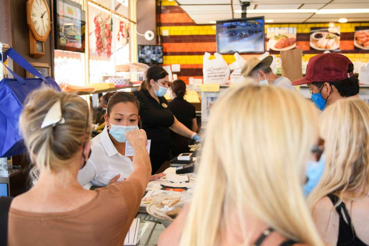 An employee checks a vaccine card for proof of Covid-19 vaccination at Langer's Deli in Los Angeles, California on August 7, 2021. - The restaurant announced that proof of vaccination would be required to dine indoors at the restaurant as Covid-19 variant causes surge in the Los Angeles area. (Photo by Patrick T. FALLON / AFP) (Photo by PATRICK T. FALLON/AFP via Getty Images)
