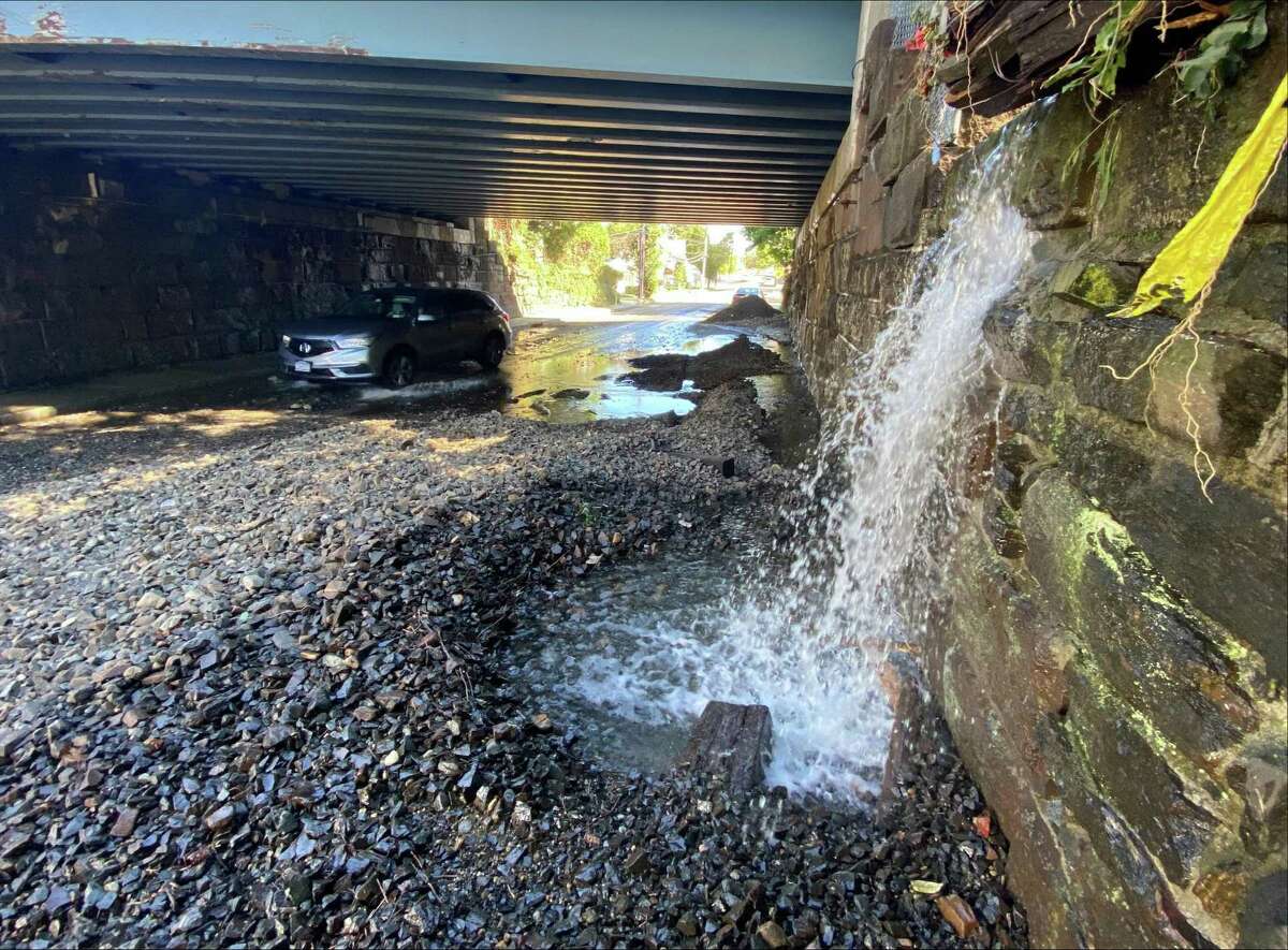 Water is pouring onto a dmaged roadway on North Water Street in the Byram section of Greenwich underneath the Metro-North tracks on Thursday morning, Sept. 2, 2021. The overnight storm was the remains of Ida. Gravel erosion from train tracks resulted in mudslide into the roadway, according to police.