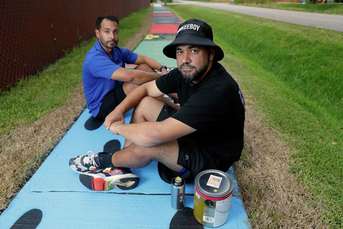 Jorge Sanchez, left, Memorial Hermann project lead, and artist Alex “Donkeeboy” Roman, right, with the sidewalk artwork by Roman along Highlawn Street, just off Tidwell Road in the Northline neighborhood Wednesday, Sep. 1, 2021 in Houston, TX. Since 2017 Memorial Hermann has focused on improving the health of Northline Community residents by promoting park usage, safety and exercise.