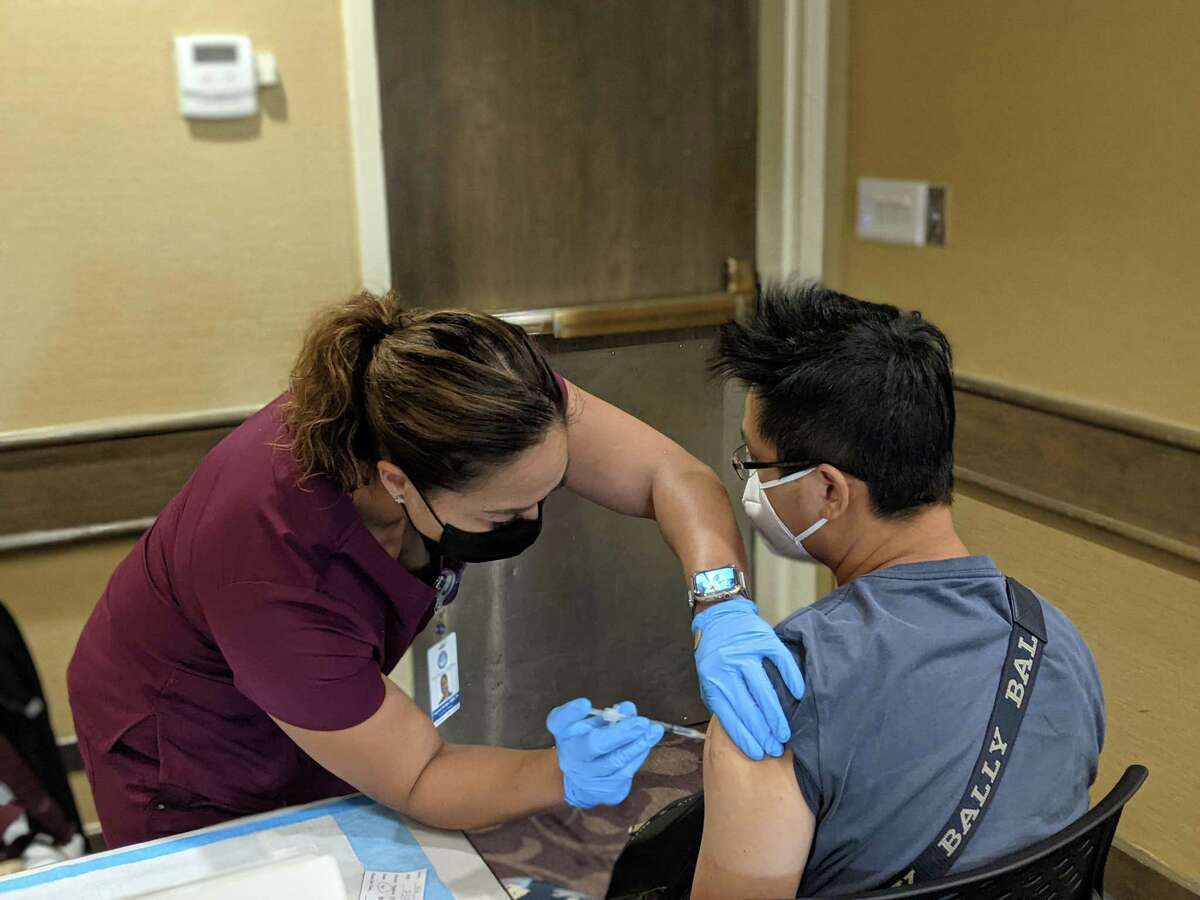 Frances Nicdao, a clinical nurse manager of the American Medical Center in Guam, administers a Pfizer vaccine dose to a Taiwanese tourist at the Hyatt Regency, a designated "vacation and vaccination" hotel.