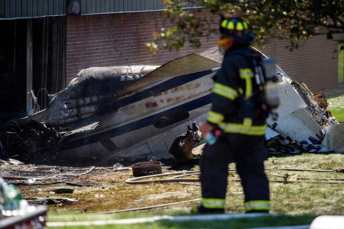 A firefighter near the wreckage of a Cessna Citation 560X aircraft that crashed into a building at the manufacturing company Trumpf Inc. in Farmington, Conn., and caught fire Thursday, Sept. 2, 2021, after taking off from nearby Robertson Airport in Plainville, Conn. The small jet crashed shortly after taking off, killing all four people aboard, officials said. (Mark Mirko/Hartford Courant via AP)