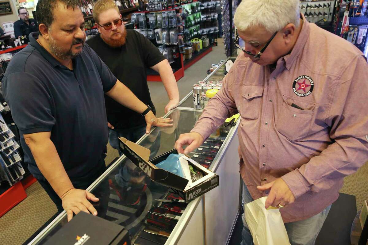 Tony Perales, right, sells a Smith & Wesson 9mm handgun to Luis Goez, left, at Ranger Firearms on Austin Highway on Friday, Sept. 3, 2021. Texas' "constitutional carry" law takes effect this week, allowing adults over 21 without criminal backgrounds to carry handguns without a license. In the middle is Mike Brotherton.