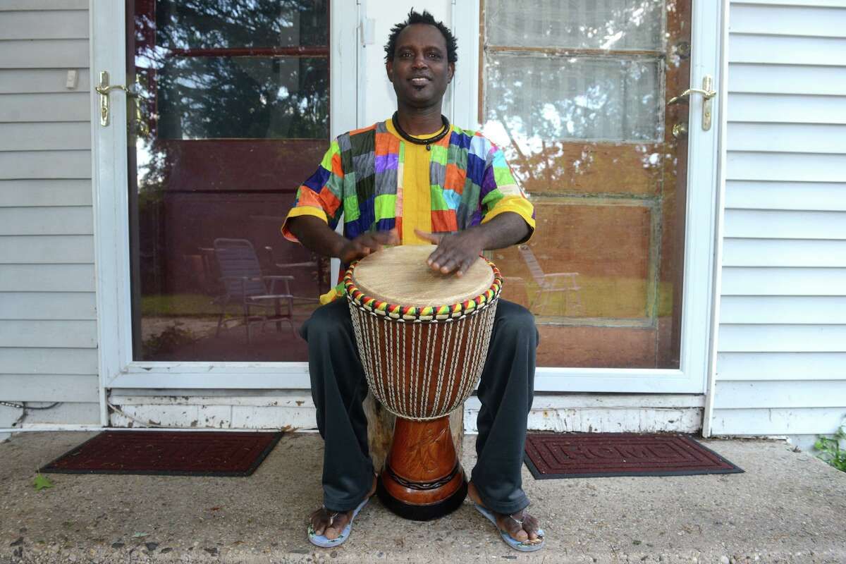 Waly Thiam plays a djembe drum in front of his home in Bridgeport, Conn. Sept. 2, 2021. Thiam recently made a return trip to his home village in Senegal to help work on construction of a new medical facility.