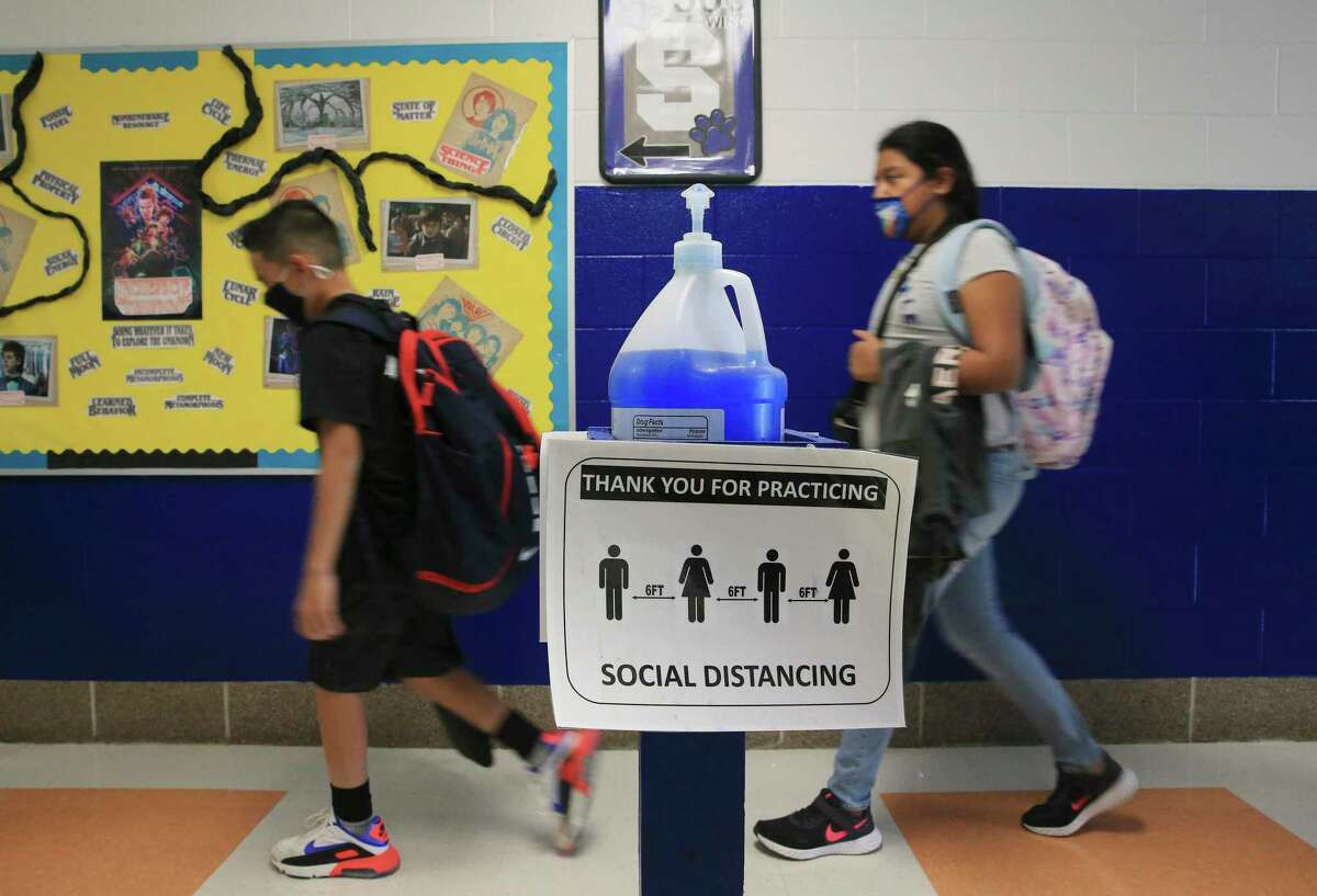 Fifth-grade students walk past a bottle of hand sanitizer and social distance reminders on their way to lunch Thursday at Savannah Heights Intermediate in Somerset ISD in Von Ormy. The district is confident it can limit coronavirus exposure at its campuses. Some districts have developed contingency plans in case large numbers of students and staff have to quarantine.