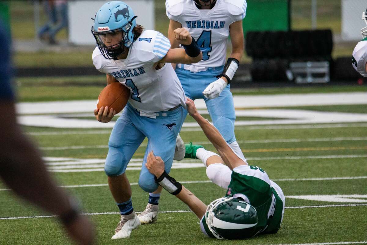 Quarterback junior Meridian Brayden Riley menerobos tekel saat pertandingan Jumat melawan Clare, 3 September 2021.