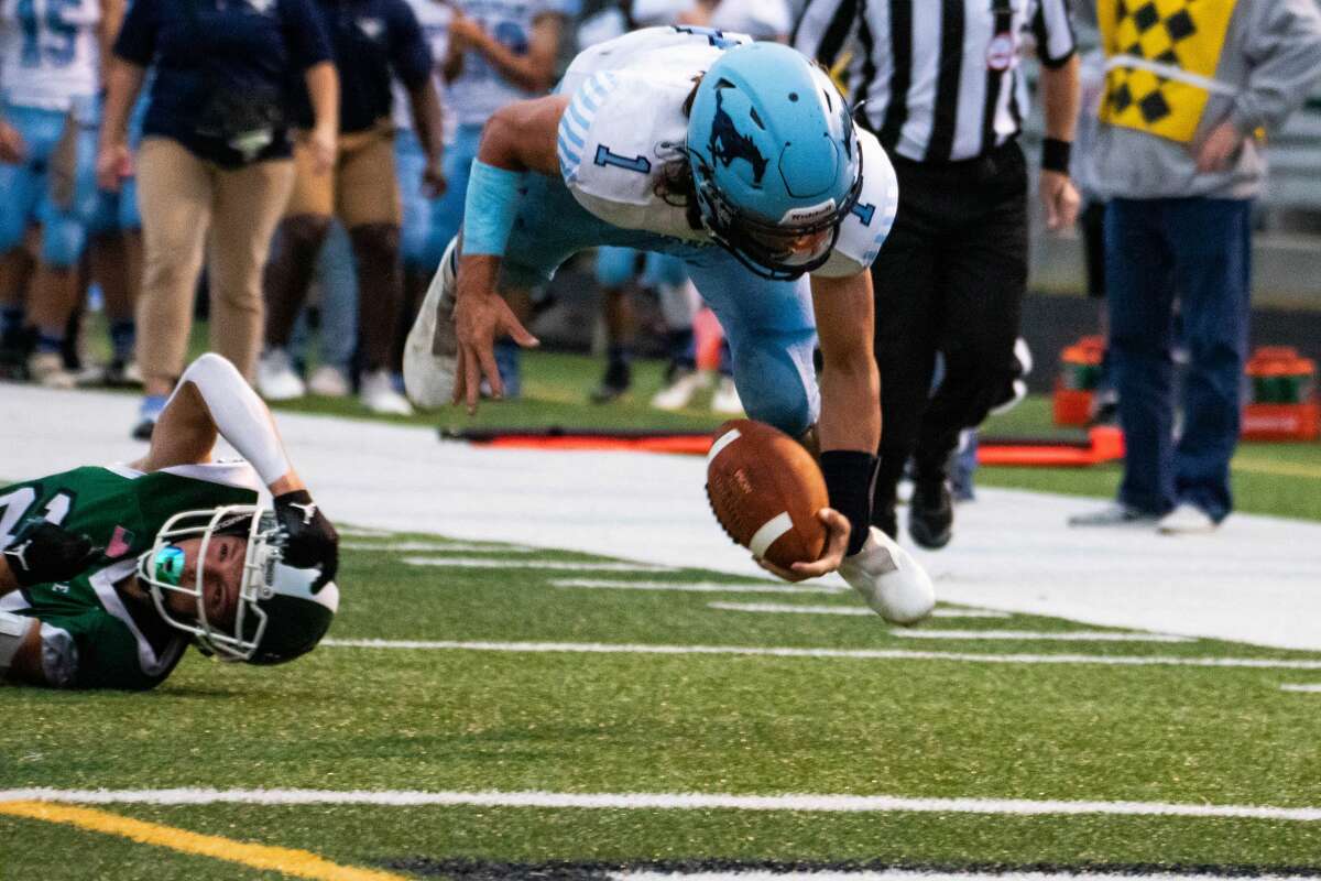 Quarterback junior Meridian Brayden Riley mematahkan tekel dan melayang ke udara menuju garis gawang selama pertandingan Jumat melawan Clare, 3 September 2021.