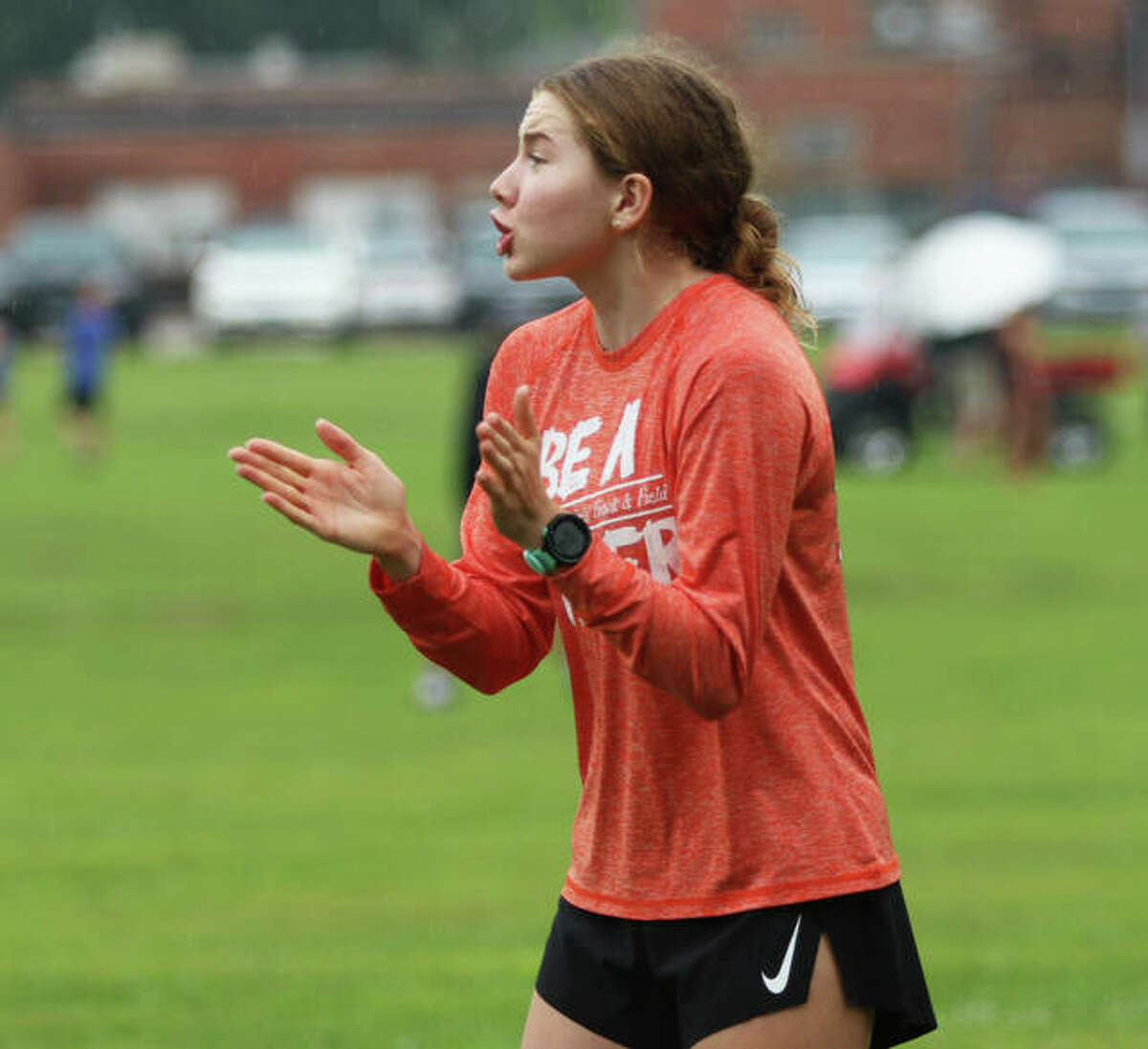 Edwardsville junior Riley Knoyle encourages her teammates approaching the finish at the Granite City Invite on Saturday morning. Knoyle, the 2020 Telegraph Cross Country Runner of the Year last season, is out with an injury.
