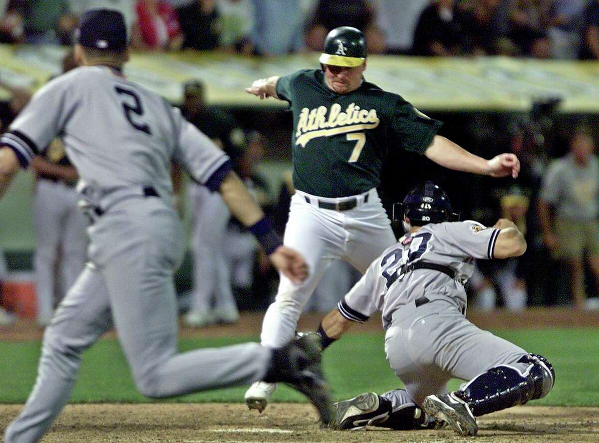 Oakland Athletics' Jeremy Giambi, center, is tagged out at home by New York Yankees' Jorge Posada, right, during Game 3 of the American League Division Series, in Oakland, Calif., Saturday, Oct. 13, 2001. Giambi tried to score from first on a double from Terrence Long in the seventh inning. At left is Yankees short stop Derek Jeter who assisted with a throw from between first and home. (AP Photo/Eric Risberg)