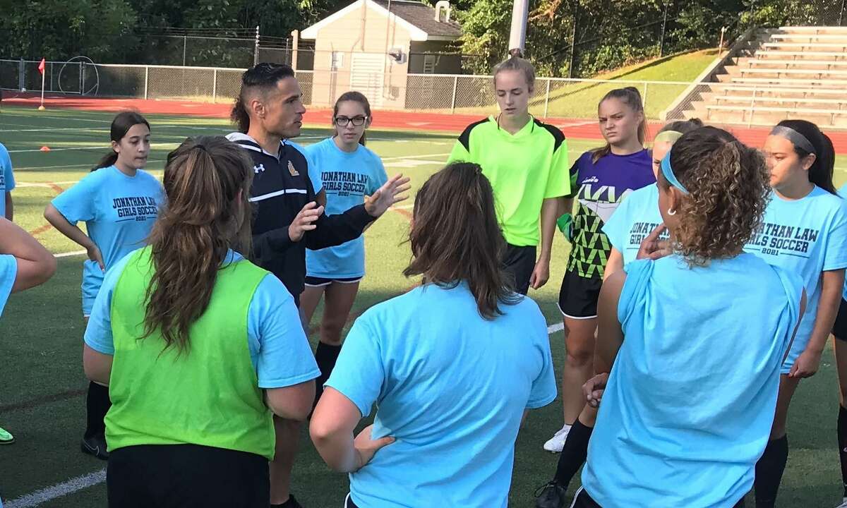 Law coach Joaquin Rodriguez goes over strategy with the Law girls' soccer team