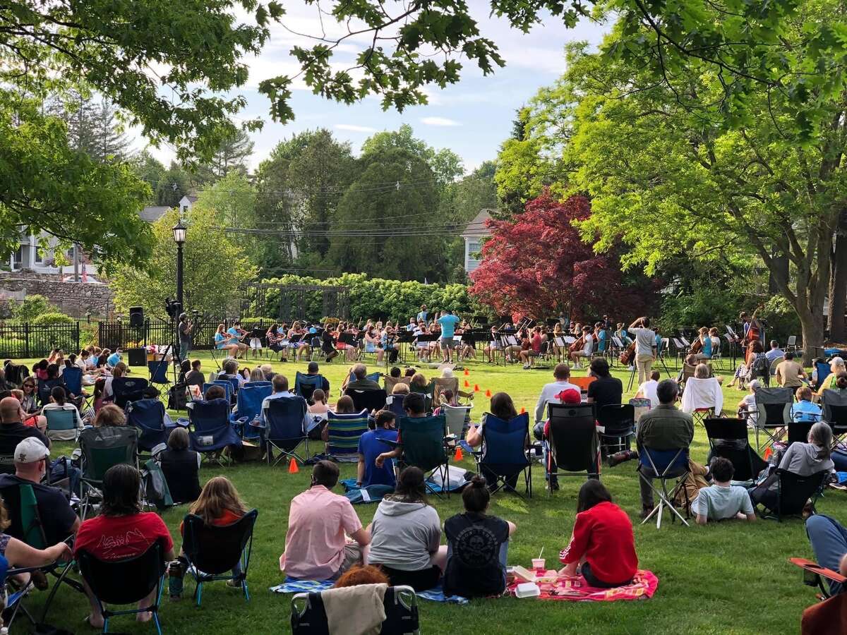 The Ridgefield High School concert orchestra and wind ensemble perform in front of spectators outside in Ballard Park.