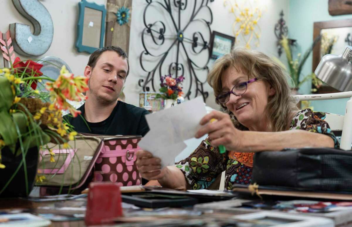 Elizabeth Waller and her son, Colton White, look at childhood pictures of the family including White's older brother, Stetson Hoskins, in the resale shop Waller runs, Wednesday, July 14, 2021, in Flint, TX. Hoskins, who was 24 at the time, was in the midst of a mental health crisis when he stepped in front of an 18-wheeler and was killed in January of 2020. Hoskins had been taken to the hospital twice in the days leading up to his death, and at one point told a doctor he was going to kill himself by stepping in front of a truck, but he was released.