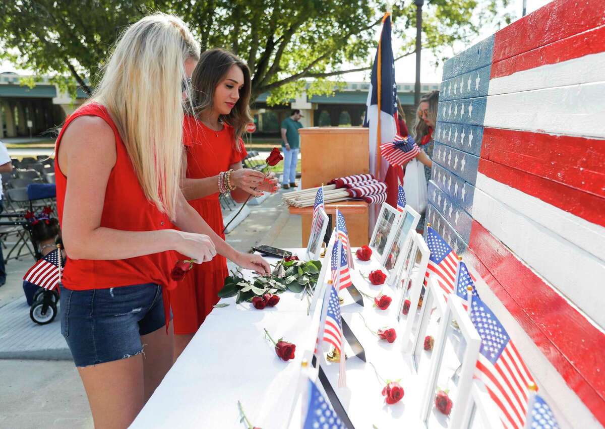 Denise Zepeda, back, helps Melissa Enloe place roses in honor of the 13 U.S. soldiers who died during an Aug. 6 attack at the Kabul airport in Afghanistan. Community members gathered at the Montgomery County War Memorial Park to remember those soldiers, sing patriotic songs and pray.