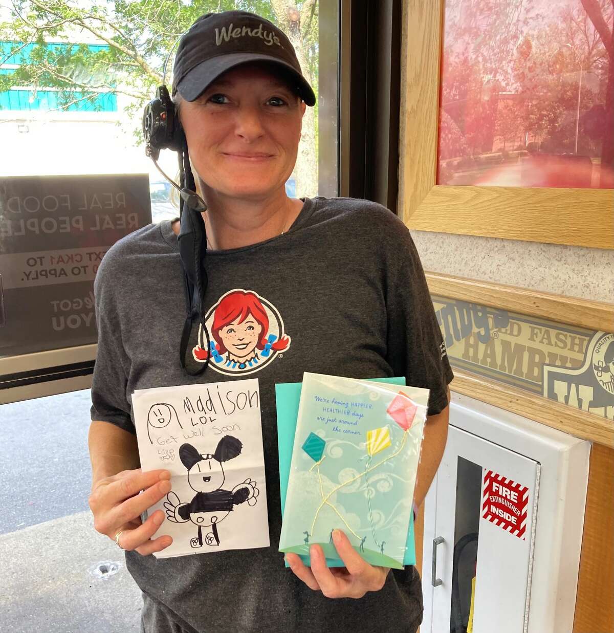 Kelly Brady, a coworker of Deborah Carpenter, holds up a card signed by the Wendy's crew and a drawing from Brady's granddaughter. Carpenter once entertained the granddaughter at the store while Brady worked. Now Carpenter is unconscious after a bike accident and police are looking for witnesses to the incident.