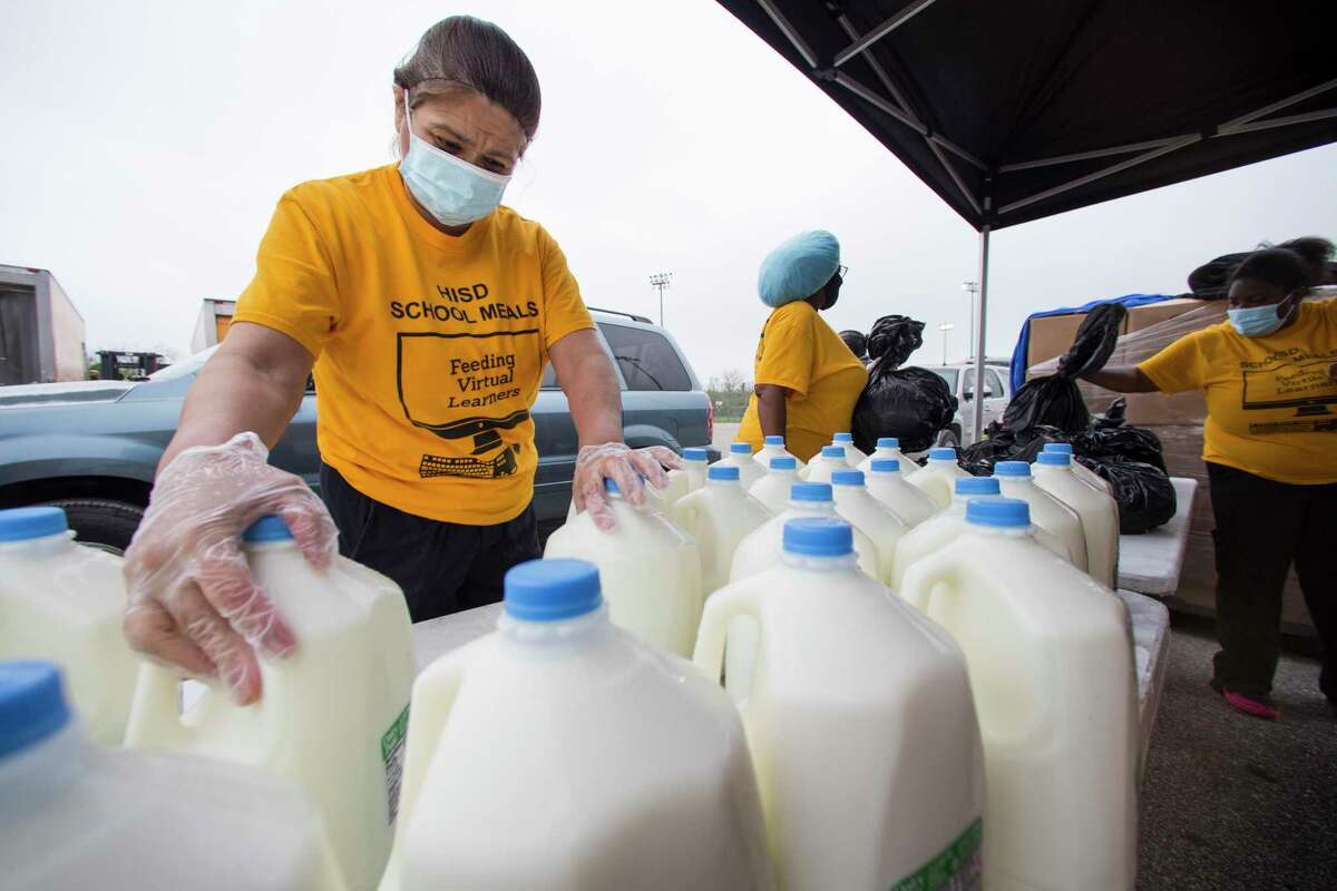 Maria Saldana moves gallons of milk on a table to place in cars during a food distribution event at Barnett Stadium Wednesday, March 24, 2021 in Houston. HISD Nutrition Services distributed student meals, family food boxes, and masks for people in the community. HISD had enough food to hand out for 4,500 students.