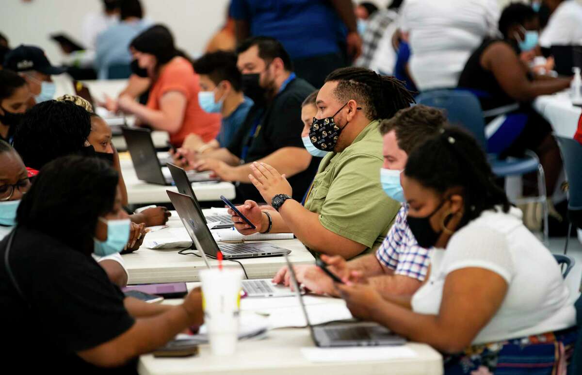 Volunteers assist people apply for both the Harris County Recovery Assistance and the Houston-Harris County Emergency Rental Assistance program during an enrollment drive, Tuesday, Aug. 3, 2021, at IBEW Local 716 building in Houston. Hundreds of people lined up outside and were seated inside to receive assistance signing up for the programs which can also be applied to online.
