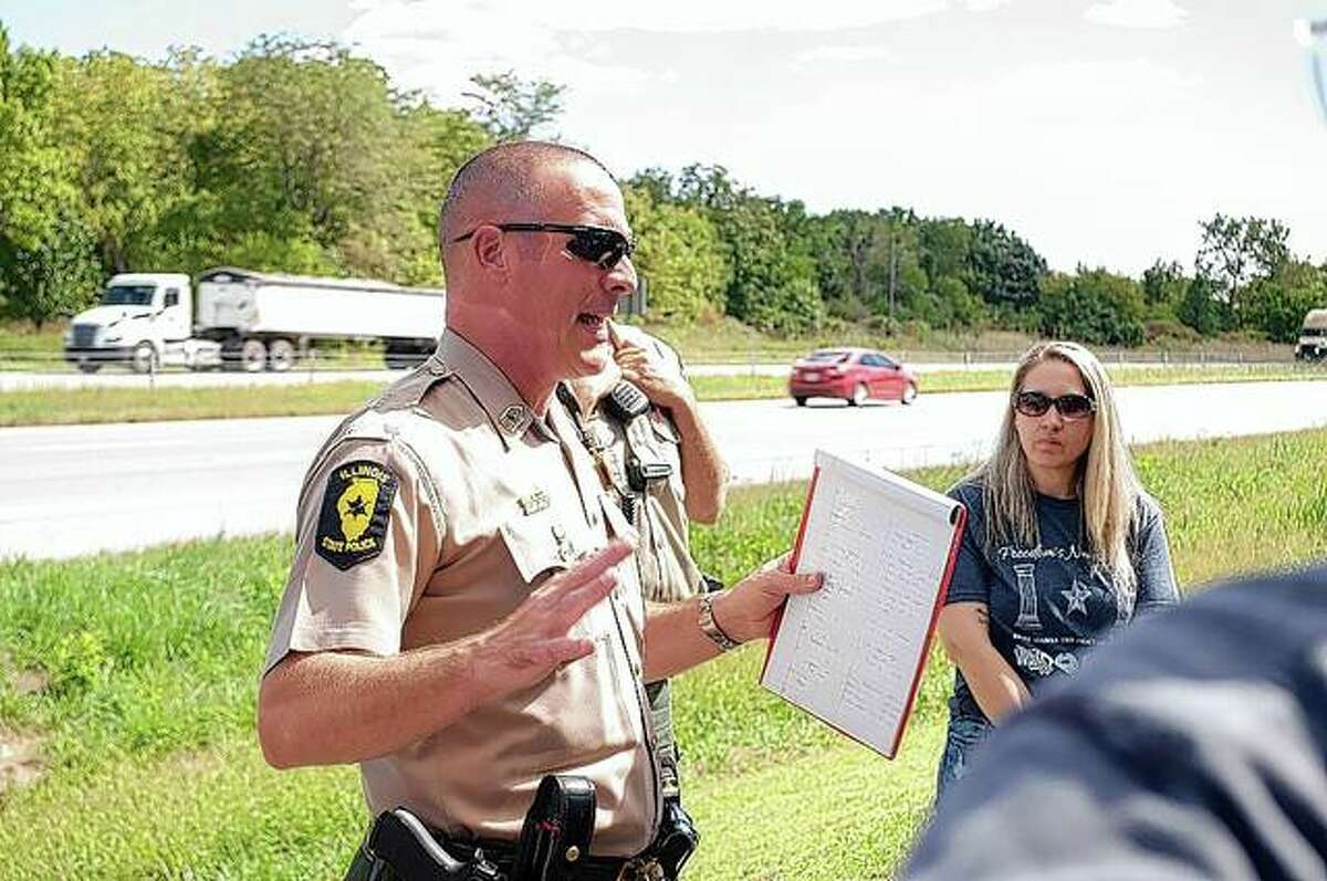 Brice Hager, Illinois State Police master sergeant, talks Thursday afternoon at the Sherman rest stop on Interstate 55 with those involved in escorting the traveling World War II memorial.