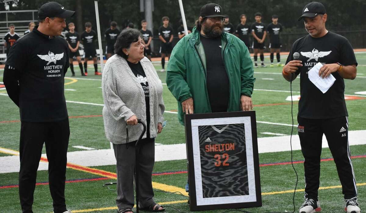 Shelton assistant boys' soccer coach Augie Sevilliano speaks to Matt Horvath's father Matthew and grandmother Patt during the ceremony to retire Horvath's jersey #32. Horvath, a 2021 graduate, died in July following a watercraft accident. He was a three-year starter for coach Isaac Montalvo and the Gaels.