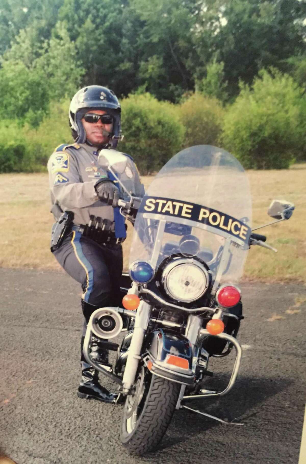 Trooper Walter Greene, Jr., stands next to his state police motorcycle in this updated photo.
