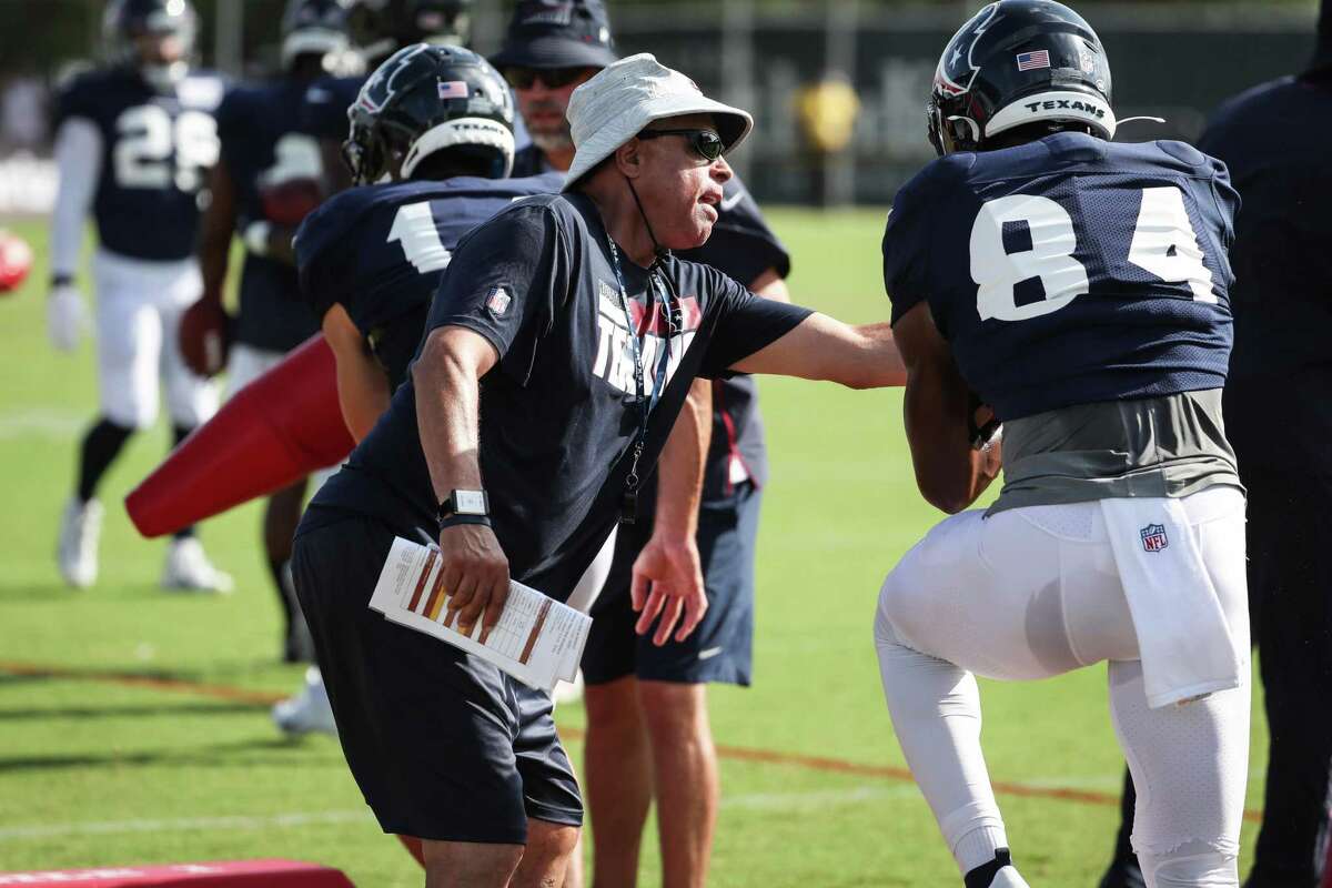 Houston Texans head coach David Culley reaches in to try an dislodge a ball carried by wide receiver Jordan Veasy (84) during an NFL training camp football practice Monday, Aug. 9, 2021, in Houston.