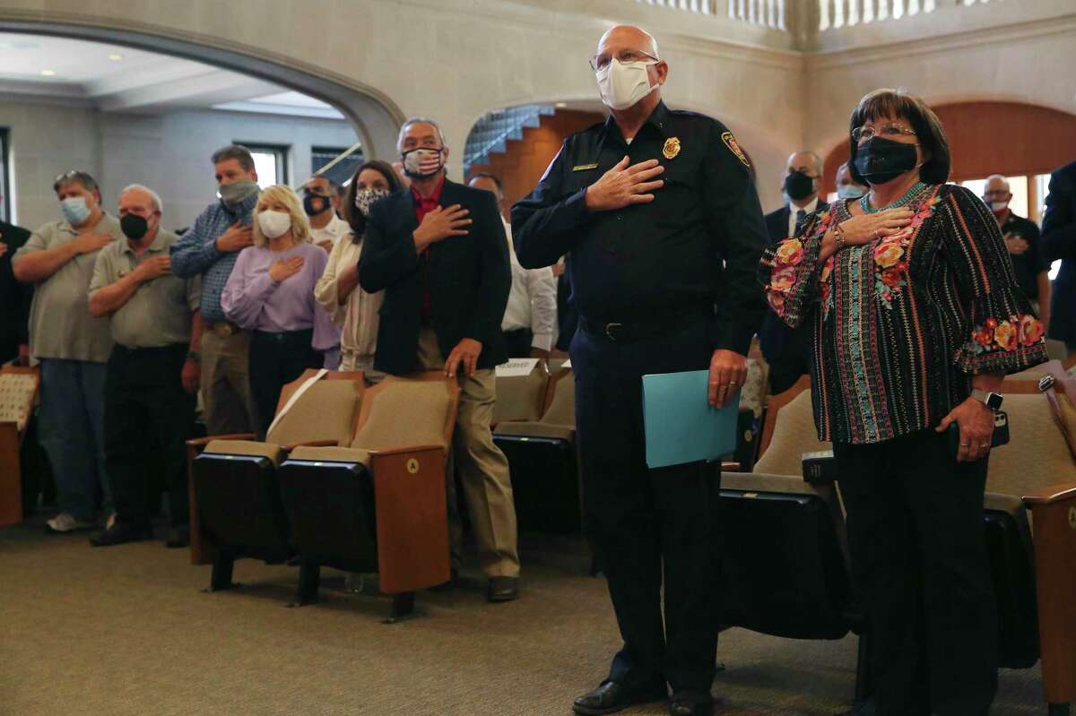 San Antonio Fire Department Head Chaplain Jerry Whitley and his wife, Marsha, salute the flag during a 9/11 Remembrance Ceremony in city council chambers, Thursday, Sept. 9, 2021. In back on the left, are SAFD personnel and their spouses, members of Texas Task Force I, who were deployed to Ground Zero, twenty years ago.