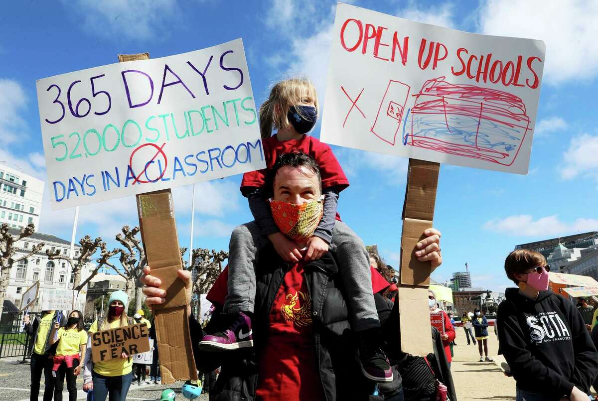 Jeff Cluett carries daughter Violet Rodgers, a kindergartner at the Chinese Immersion School at DeAvila Elementary School in S.F., during a rally in March demanding that schools reopen.