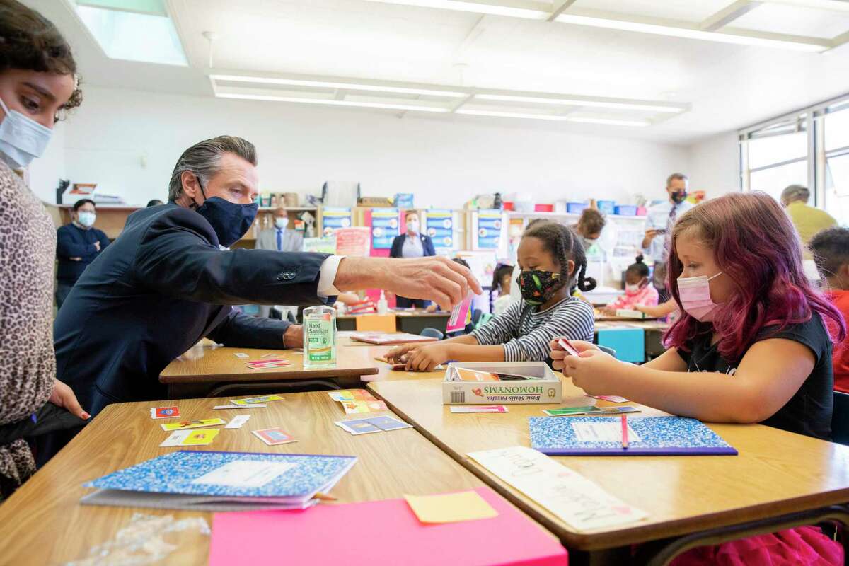 California was more stringent than many states about requiring masks for all indoor settings. Here Gov. Gavin Newsom visits with second-graders at an Oakland school in August.