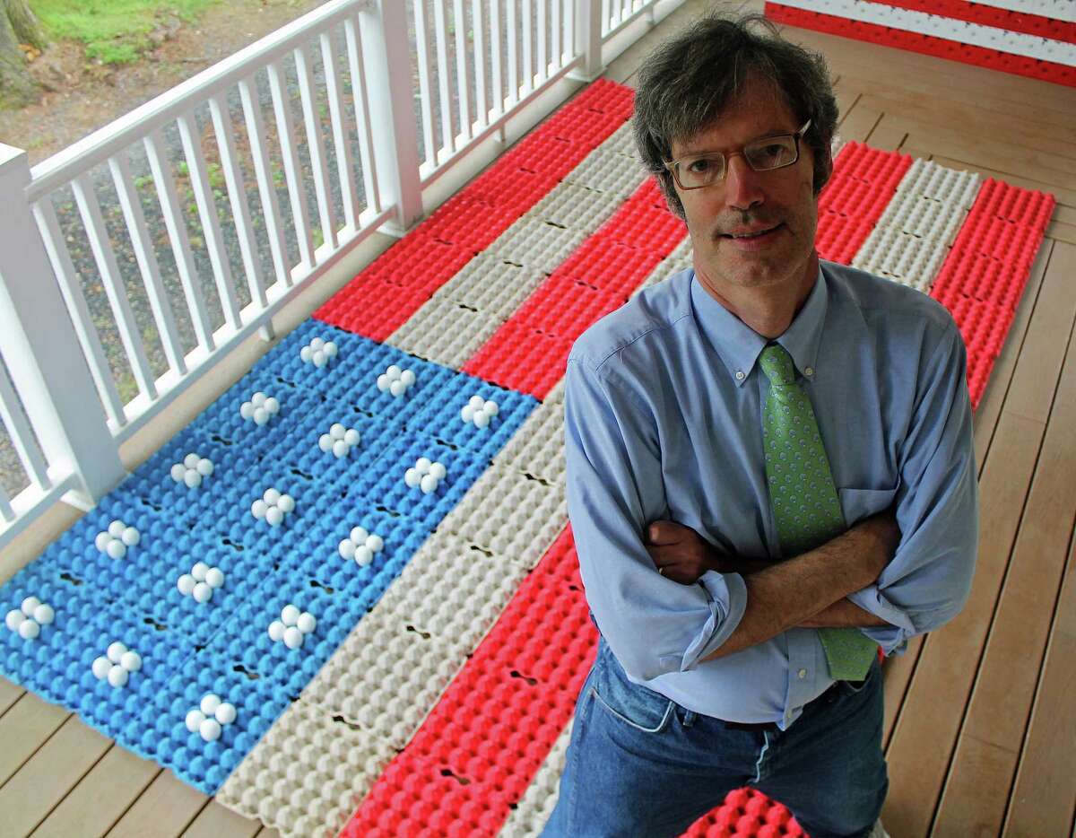 Robert Carley on the porch of his Darien, Connecticut, home, where he creates flag art out of everyday objects, including egg cartons and eggs (background). Carley just released the art book “Liberated: Freed from the Flagpole. The Metamorphosis of the Flag Since 9/11.”