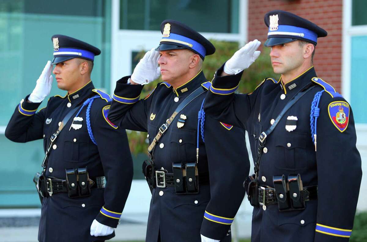Stamford Police Officers Damein Rosa, left, Lieutenant Douglas Deiso, and Sergeant Kevin Lynch, right, salute during a 9/11 memorial on the 20th anniversary of the terrorist attacks in front of police headquarters in Stamford, Conn., on Saturday September 11, 2021.